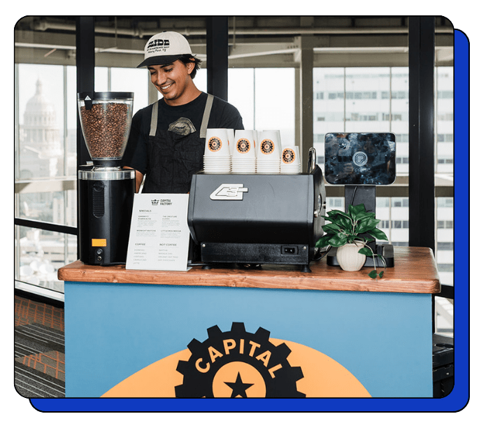 Barista at amobile coffee counter with 'Capital' branding in an urban setting