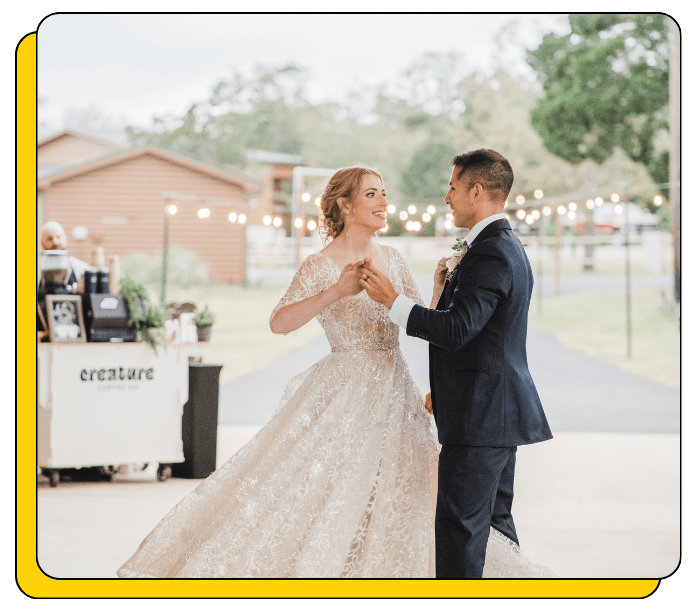 Couple in wedding attire dancing outdoors with blurred background, and a mobile coffee cart serving the best lattes to their friends and family