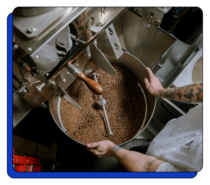 Person operating a coffee roasting machine with coffee beans inside