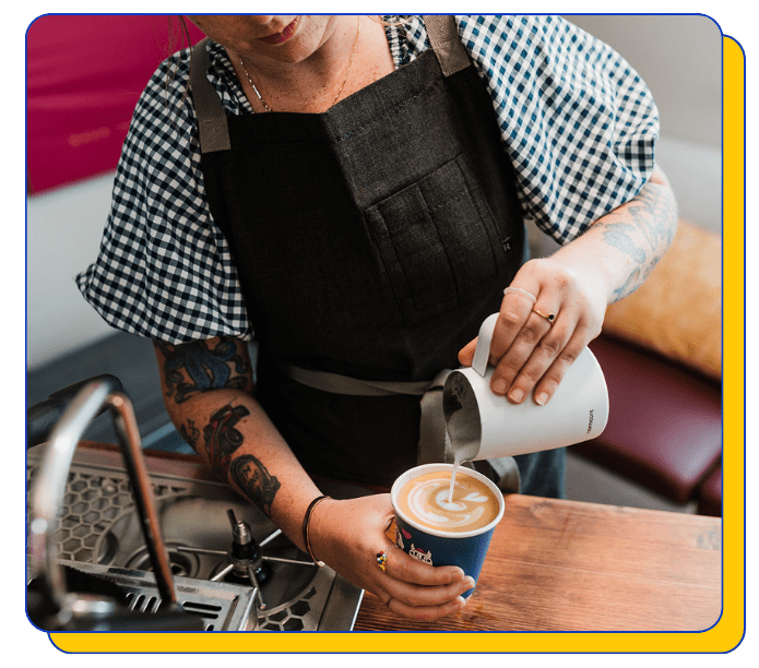 Barista pouring a latte into a cup in a mobile coffee shop event