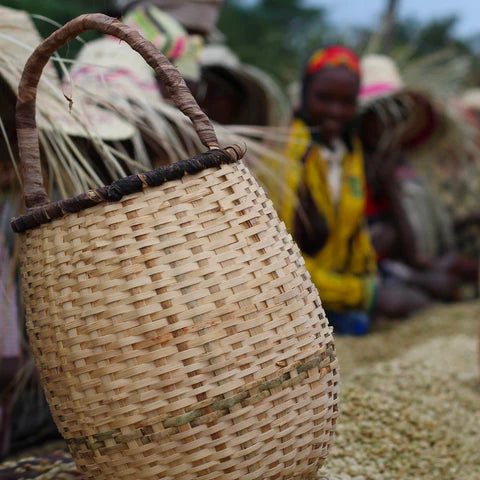 Woven basket with a blurred background of people wearing colorful hats. Ethiopia 