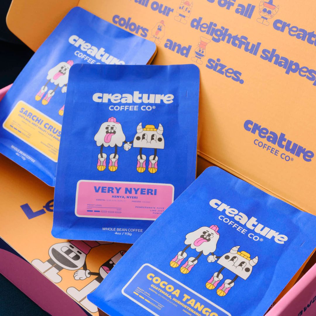 Blue creature coffee bags from creature Coffee Co with cartoon characters on a colorful background