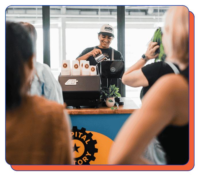 Barista behind a mobile coffee cart counter serving coffee to customers in a casual setting at an office event, for a corporate gathering, custom-branded cart