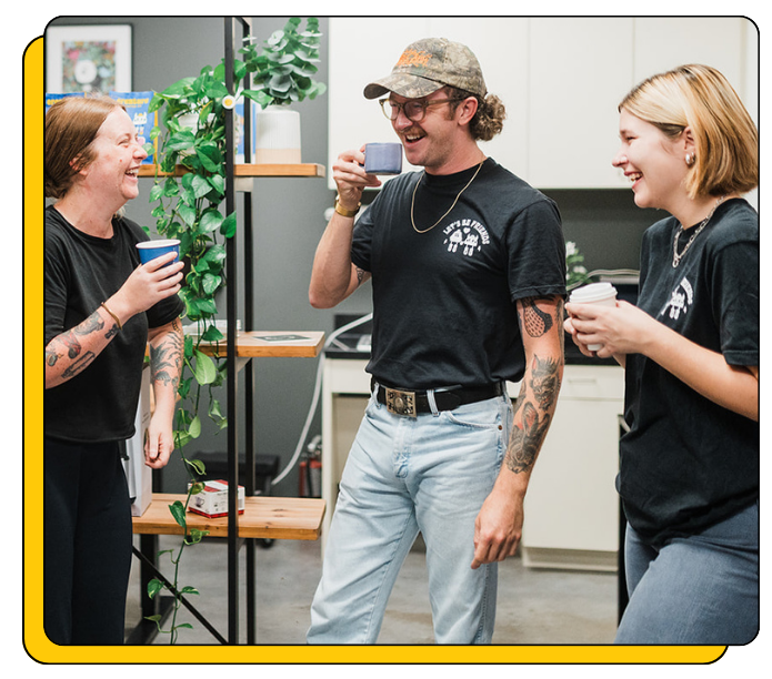 Three Creature Coffee baristas in a casual setting, two holding drinks and one taking a selfie before delivering coffee catering to an event. 